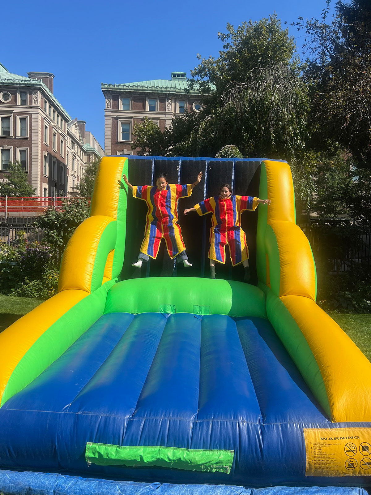 Two women hanging on blow up slide